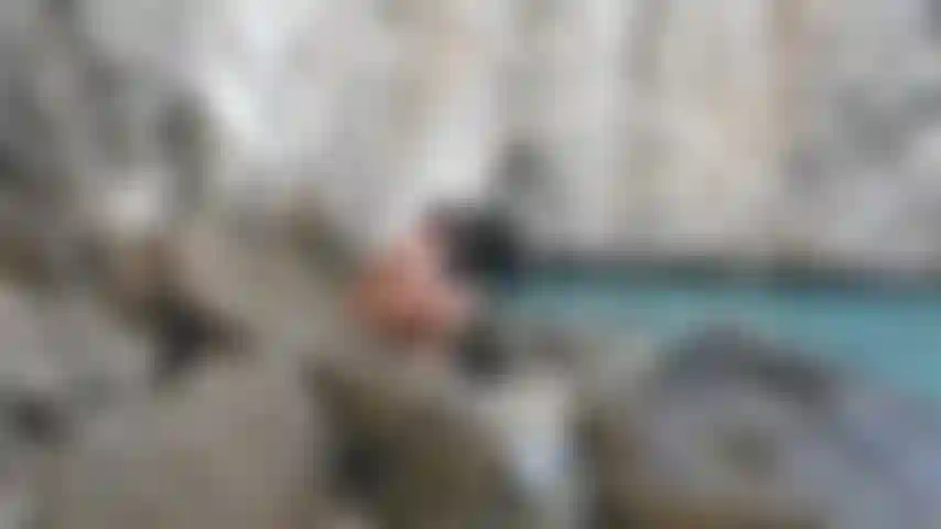 Je marche nu sur des rochers pendant mes vacances, exhibant mes lignes de bronzage.