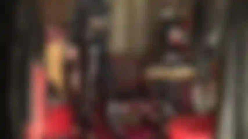 Fétichiste du pvc - entièrement habillée de vinyle noir brillant, la maîtresse taquine le fétichiste du pvc avec un jean brillant, des talons et un long manteau.