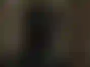 Une maîtresse à capuche en latex perverse taquine ta bite et tes tétons pendant qu'elle porte un masque en latex noir brillant.