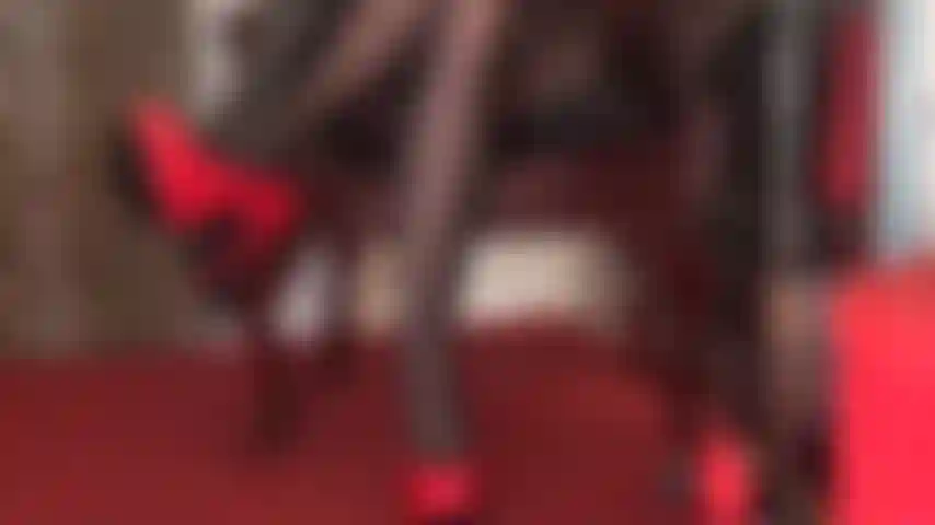 Des talons aiguilles rouges brillants, des gants en cuir noir et des jambes en collants noirs sont une pure séduction.