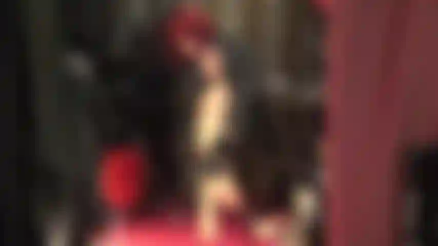 Une déesse en cuir vous taquine avec ses jambes chaudes dans des collants beiges brillants et des sandales rouges à brides à la cheville.