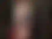 Maîtresse en manteau de cuir blanc, robe en vinyle rouge et collants, portant un de ses gros strapons blancs pour vous faire baver.