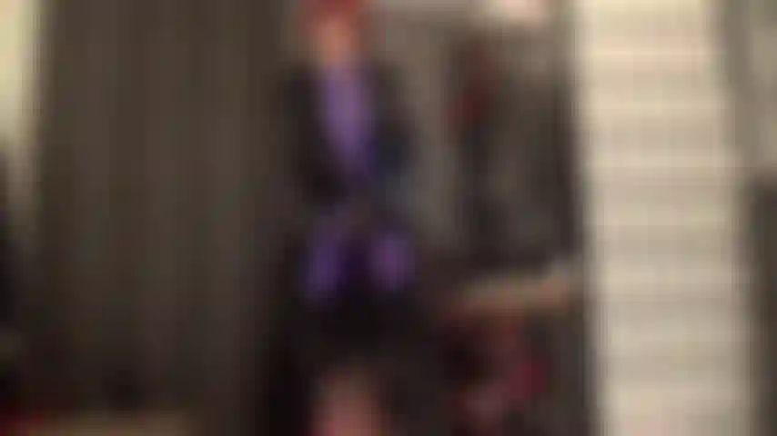 Un manteau en pvc brillant et épais sur une combinaison en leohex violet avec un strapon stryker et des bottes.