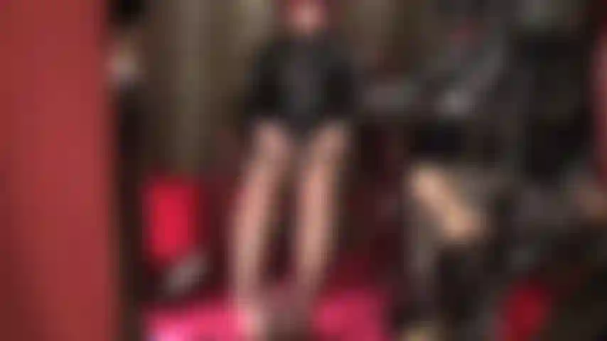 Maîtresse caresse deux bites - vêtue de pvc brillant et de collants marron, ses pieds sont enroulés autour d'une bite noire tandis que maîtresse caresse son gode-ceinture blanc à mains nues.