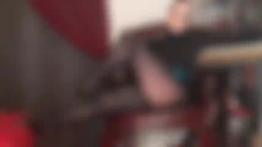 Maîtresse séduit avec ses jambes en collants noirs brillants et un décolleté sexy en soutien-gorge en dentelle.