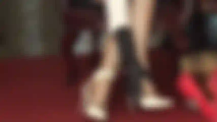 Des sandales blanches à lanières et des collants brillants taquinent les pieds.