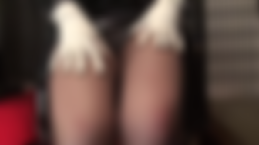 Une allumeuse en noir et blanc : de jolis talons blancs à brides à la cheville, des gants blancs et un body blanc contrastent avec le pvc noir brillant. Une maîtresse aguicheuse avec des vues sous la jupe et des jambes en collants marron café.