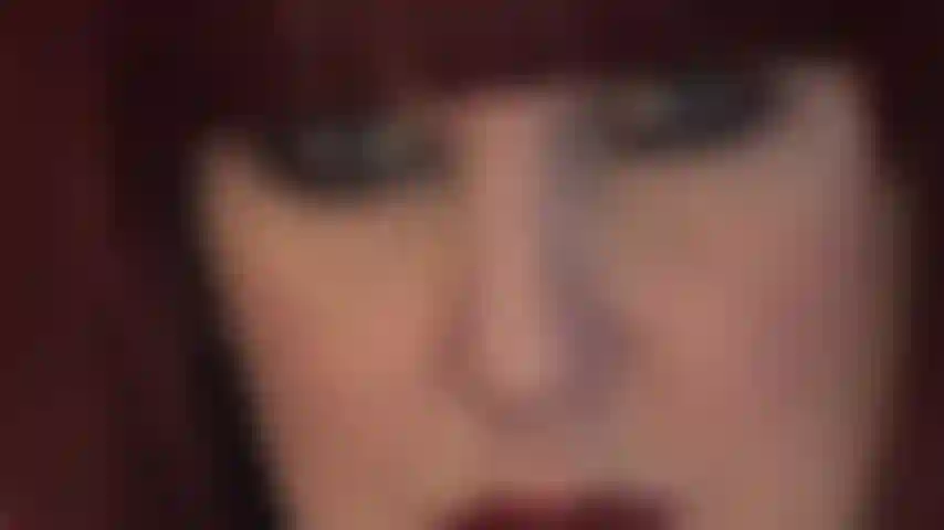 Le visage hypnotique de maîtresse - des lèvres rouges pulpeuses et des yeux bleus perçants qui regardent droit dans votre âme.