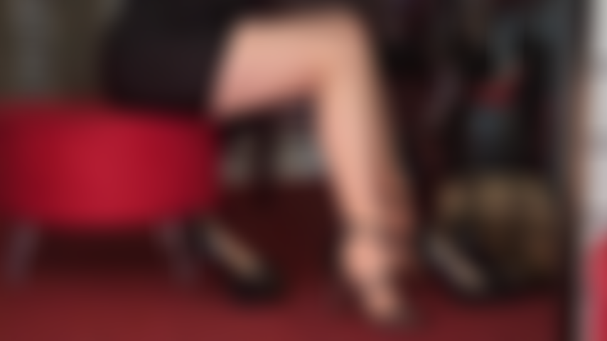 Des jambes et des pieds séduisants dans des collants bronzés et plusieurs paires de talons hauts noirs sexy.