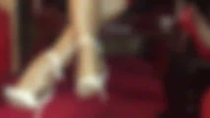 Des jambes de collants incroyablement brillantes en couches de nylon doré et des sandales blanches à bride à la cheville.