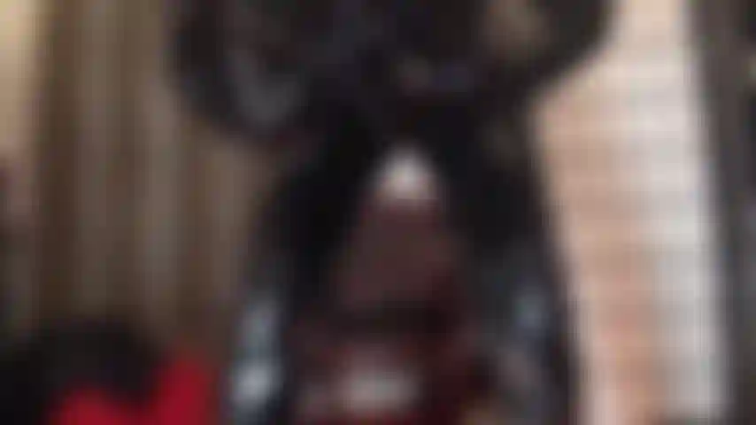 La perfection du pvc brillant - la maîtresse taquine dans une combinaison en pvc noir moulante, des bottes et des gants.