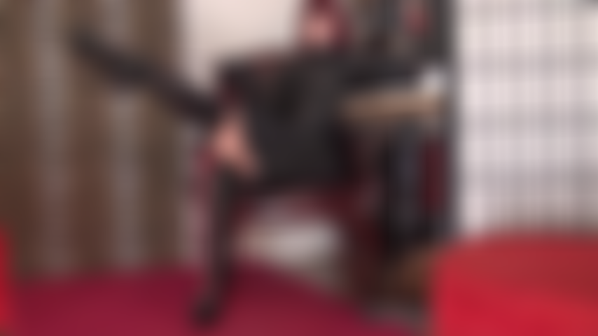 Une déesse sensuelle du cuir adorée avec des bottes lacées, une jupe jusqu'aux genoux, des gants courts et une cravache.