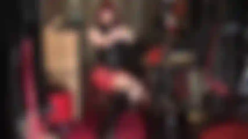 Fétichiste du latex - tenue en caoutchouc rouge et noir avec des bottes aux genoux.