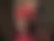 Maîtresse vivian, vêtue de latex rouge brillant, jambes nues, talons hauts, longs gants brillants.