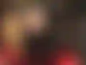 Une vue sous la jupe en vinyle noire sexy et large de la maîtresse révèle des collants noirs transparents et de hautes bottes brillantes.