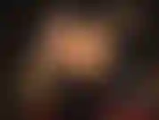 Une maîtresse en pvc brillant en bottes avec un énorme strapon noir.