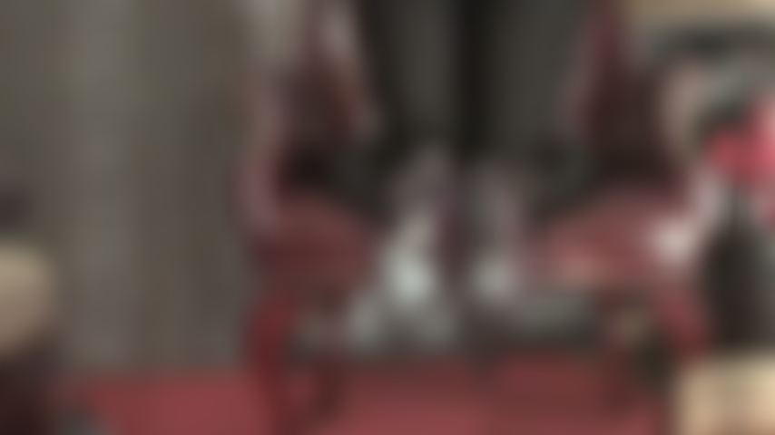 Maîtresse enlève ses talons, ses pieds en collants transparents pendent de la chaise.