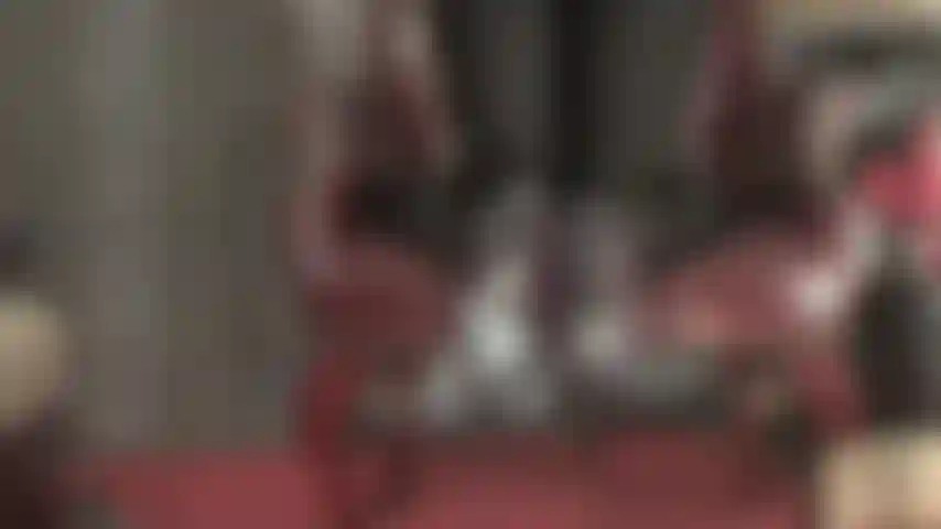 Maîtresse enlève ses talons, ses pieds en collants transparents pendent de la chaise.