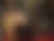 Perruque noire et tenue fétichiste en pvc/vinyle brillant avec des bottes hautes et un énorme strapon pour un pegging dur.