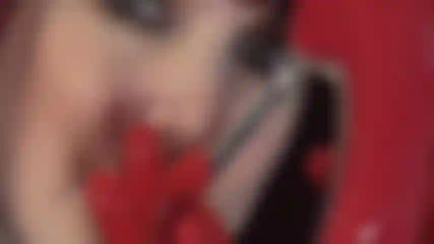 Des gants fétichistes en latex rouge pervers sur des escarpins vernis à talons en acier rouge et une bite noire qui taquine.