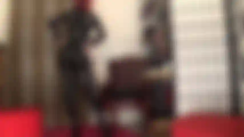 Une déesse adoratrice en combinaison moulante en pvc noir, corset et bottes jusqu'aux cuisses.