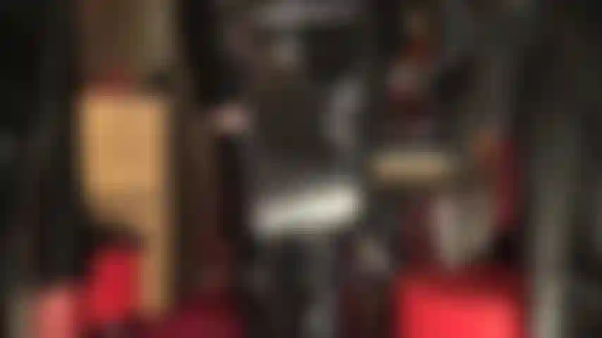 Maîtresse fétichiste en pvc brillant avec cravache et bottes au-dessus des genoux.