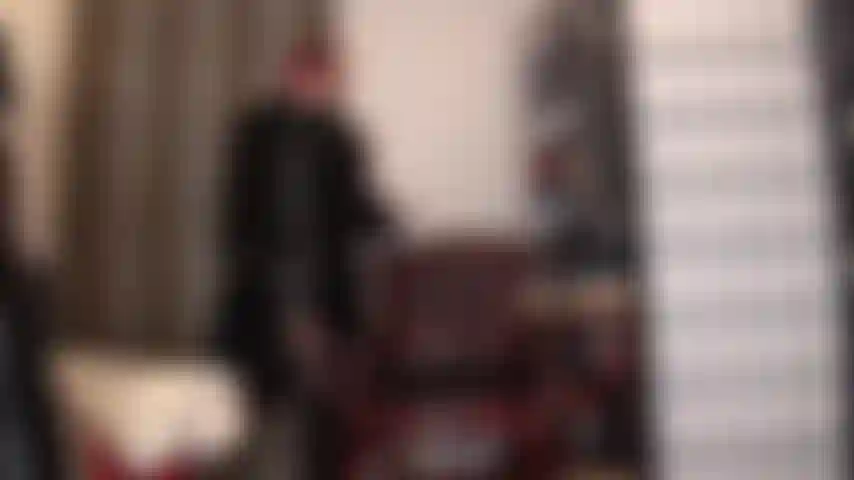 Amoureuse de la fourrure - voici un merveilleux mélange de tissus, maîtresse habillée tout en noir, robe en pvc brillant, gants en cuir et long manteau de fourrure, jambes en collants noirs et bottes jusqu'aux genoux.