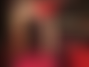 Une allumeuse sensuelle et une adoration du corps en rouge et noir - la maîtresse porte une robe sexy avec un corset en cuir, des collants brillants nude et des escarpins rouges brillants.