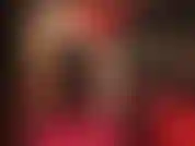 Une allumeuse sensuelle et une adoration du corps en rouge et noir - la maîtresse porte une robe sexy avec un corset en cuir, des collants brillants nude et des escarpins rouges brillants.