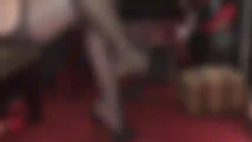 Des mules en cuir noir à talons hauts de maîtresse de culte, des pieds et des jambes galbés en collants porte-jarretelles.