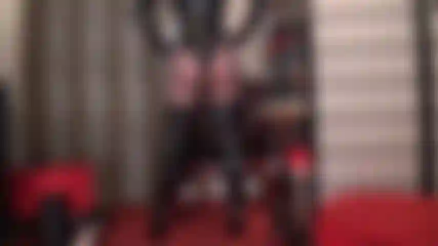 Des courbes brillantes de perfection - une séductrice brillante affiche ses courbes de perfection dans un body string en pvc, de hautes bottes au-dessus des genoux et des collants noirs transparents.