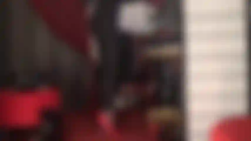 Talons aiguilles fétichistes rouges et string en dentelle rouge sur combinaison noire moulante.