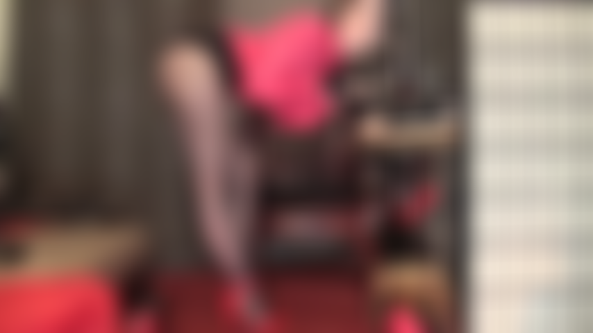 Maîtresse passe ses mains gantées sur une grosse bite tout en affichant ses jambes incroyables dans des collants noirs transparents et des talons aiguilles rouges à lanières.