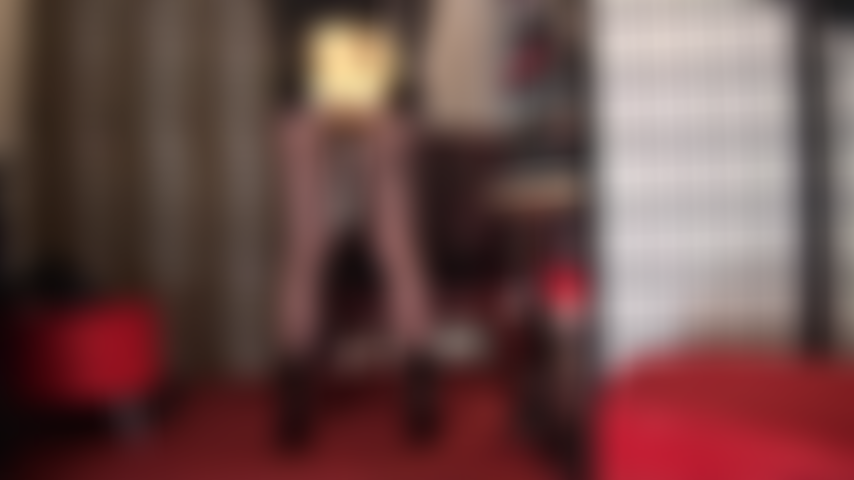 Maîtresse montre ses fesses dans un short chaud en métal doré brillant, ses jambes puissantes dans un collant noir transparent, associé à de courtes bottines noires vernies.