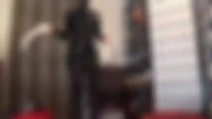 Fétichiste du latex et du caoutchouc - une maîtresse vêtue d'une robe en latex noir et d'une cagoule en caoutchouc ajoute une paire de gants en latex blanc pour une traite intensive de la bite.