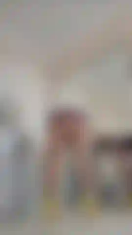 Robe en latex très courte, collants et seins taquins.