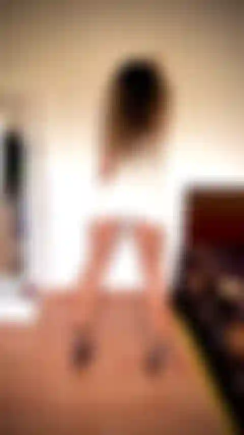 D'incroyables mollets et ischio-jambiers fléchissant, portant une robe blanche courte et serrée, penchée sur le mur, sans culotte.