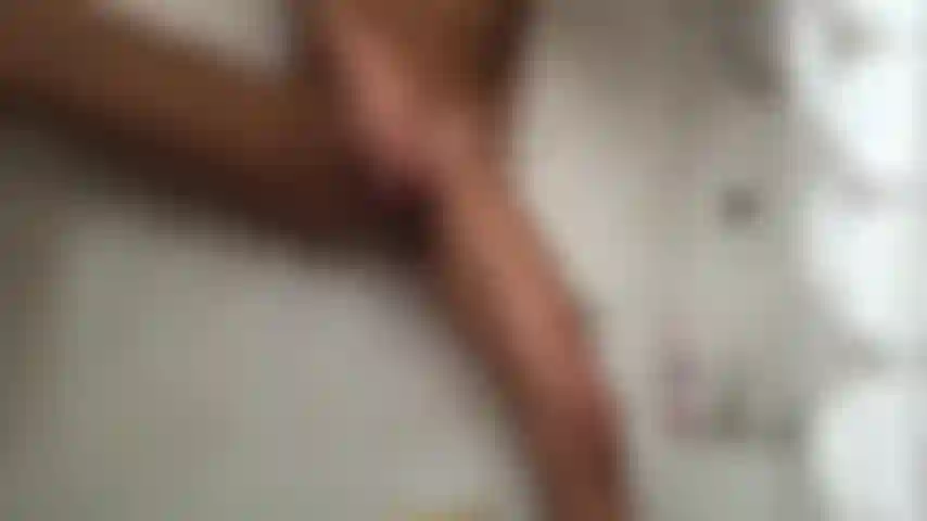 Chatte jouant avec un gode sous la douche, vue de face, jambe levée.